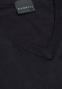 Dunkelblaues V-Ausschnitt-Pullover aus Strickstoff. Besitzt einen gerippten Kragen und ein Etikett mit "bugatti" in weißer Schrift, das die Textur hervorhebt.