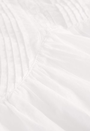 Biały materiał z zakładkami i zebranym fakturą, ukazujący lekkość i powietrzność oraz miękką, gładką powierzchnię.