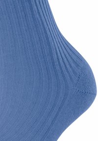 Calzino blu a coste con una texture morbida, caratterizzato da una vestibilità aderente e un tallone liscio. Il materiale appare elastico e confortevole.