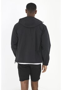 Black hooded jacket in lightweight material, featuring elastic cuffs and a drawstring hem. Worn with black shorts, minimal detailing.