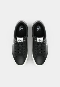 Zwarte leren sneakers met witte rubberen zolen, voorzien van een vetersluiting, logo op de tong en een gladde textuur. Eenvoudige en moderne vorm.