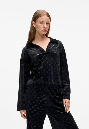 Set di abbigliamento loungewear in velluto nero composto da una maglia con colletto, scollatura a V e maniche lunghe, decorata con un motivo sottile, e pantaloni con elastico in vita.