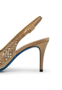 Scarpa con tacco alto in metallo dorato, con cinturino slingback, decorata con borchie trasparenti e argentate, caratterizzata da una suola blu e un tacco affusolato.
