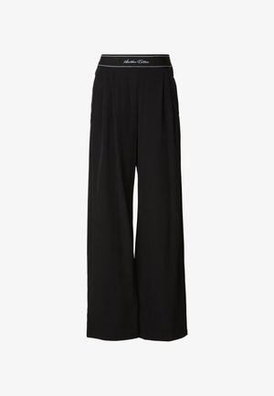 Mustat leveälahkeiset housut, valmistettu pehmeästä kankaasta, jossa on kontrastivärinen vyötärönauha valkoisilla kirjaimilla ja rypytyksiä edessä.