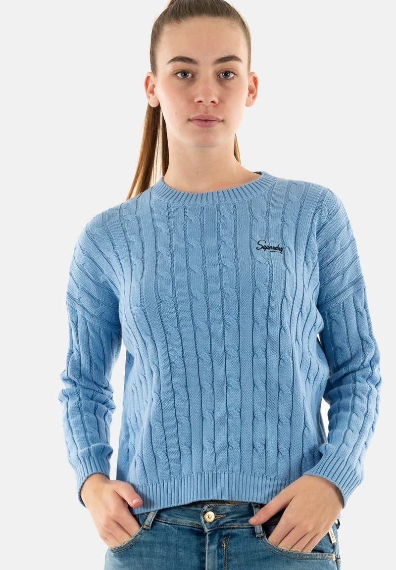 Suéter de punto azul claro con patrón de trenzas, puños y dobladillo acanalados, escote redondo, que presenta un pequeño logo bordado en el pecho.