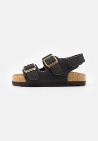 Svart sandal med doble justerbare spenner, korkfotbed og teksturert gummisåle. Åpen bakdesign for enkel påføring.