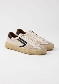 Sneaker beige con dettagli in pelle nera, tomaia in tela testurizzata, punta arrotondata e suola intrecciata beige. Visibili lacci e dettagli del logo.