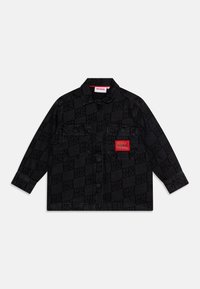 Giubbotto in denim nero con motivo a scacchiera e logo "HUGO", due tasche frontali, chiusura con bottoni e un dettaglio etichetta rossa.