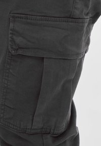 Donkergrijze cargobroek met een zijzak met klep, gemaakt van stevig materiaal, met opvallende gestikte naden en een gestructureerde vorm.