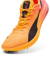 Orange l�öparskor med överdel i lätt mesh, svarta detaljer och spikplatta. Har klara snören och en vadderad krage.