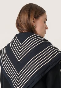 Marineblå tørklæde med hvide diagonale striber, der ligner et chevronmønster. Blødt stof, elegant hængende omkring skuldrene.