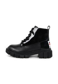 Botines de charol negro con suela gruesa negra, diseño de cordones y un detalle de logo en contraste en el tacón.