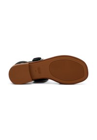 Sandal nera con parte superiore liscia, cinturino regolabile e suola piatta in gomma color beige con un motivo testurizzato e dettagli di branding.