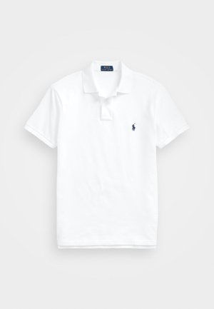 Hvit polo-skjorte laget av bomull. Har en klassisk krage, treknappslukking, korte ermer og en liten marineblå logo på brystet.