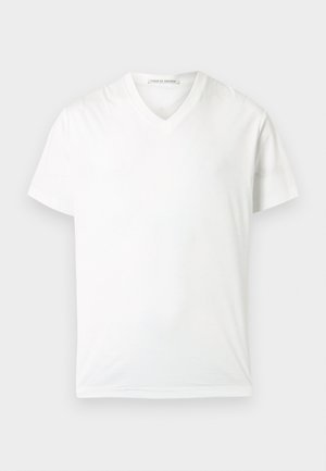 Schlichtes weißes T-Shirt mit kurzen Ärmeln und V-Ausschnitt, flach liegend mit einem sichtbaren Etikett im Kragen auf hellem Hintergrund.