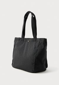 Sac fourre-tout noir en tissu texturé, doté de deux poignées et d'un design minimaliste sans quincaillerie ni accents visibles.