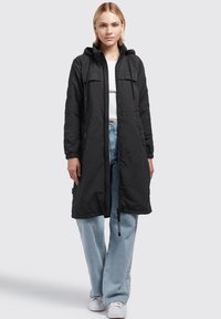 Black long coat with a zip closure, adjustable hood, and two front pockets. Features a smooth texture and a minimalist design.