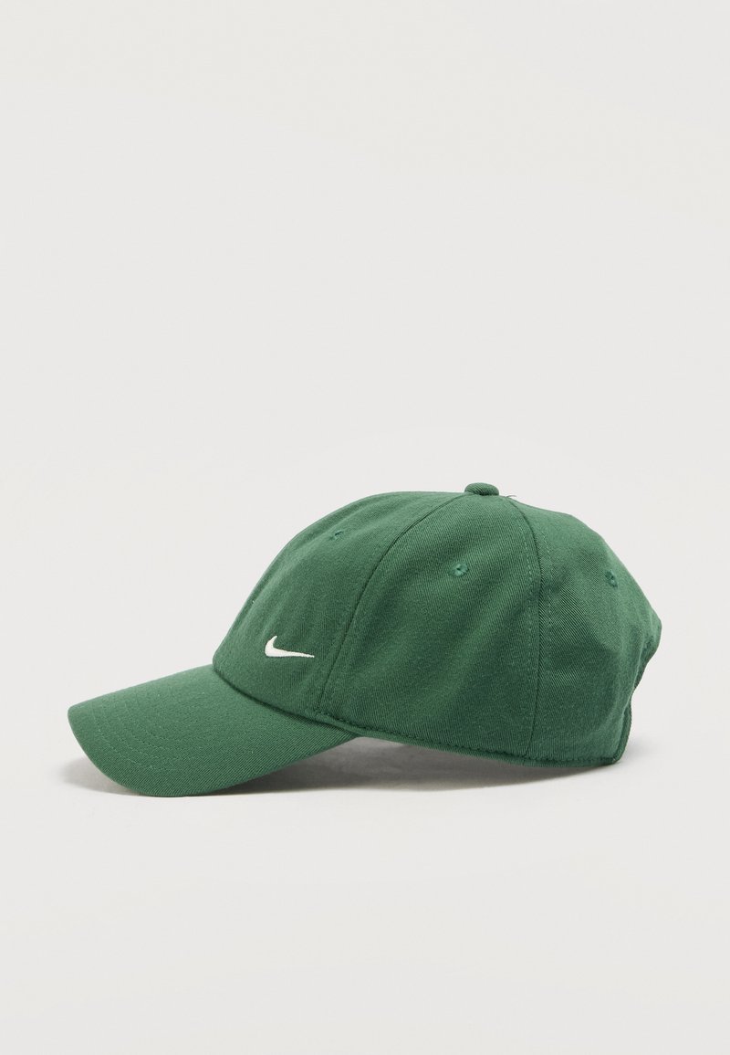 Green Nike baseball cap with curved brim and white embroidered swoosh logo on front, shown from left side on white background.