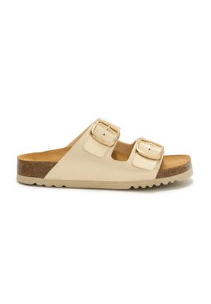 Beige slidesandal med korksål, to justerbare stropper med spænder og en tekstureret gummisål, vist fra siden på en hvid baggrund.