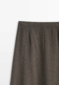 Jupe en laine gris foncé avec une ceinture droite et des détails subtils de coutures verticales sur fond blanc.