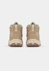 Barna velúr és szövet túracipők párnázott bokagallérral, texturált talppal és Gore-Tex felirattal a hátsó részen.