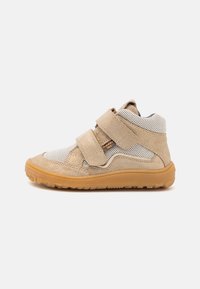 Pantof beige tip sport cu panouri din plasă, două benzi velcro și talpă din cauciuc. Are o finisare din suede texturat și un design cu vârful rotund.