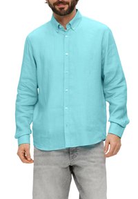 Helles blaues Hemd aus Leinen mit klassischem Kragen, langen Ärmeln und entspannter Passform, getragen mit grauen Jeans.