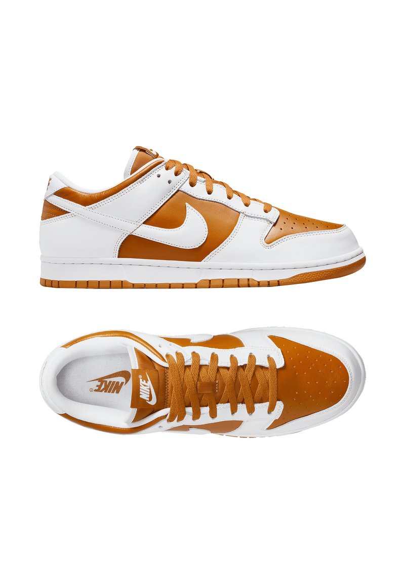 Baskets en cuir avec un blocage de couleurs blanc et marron. Caractéristiques : embout perforé, accents texturés et semelle en caoutchouc. Logo Nike visible.