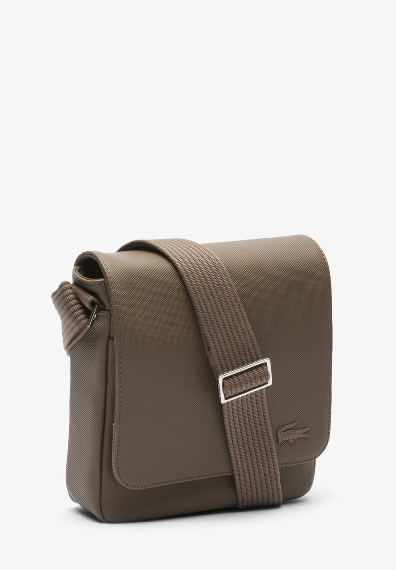 Sac bandoulière marron texturé avec rabat, sangle réglable et quincaillerie argentée. Présente un logo discret sur le devant.