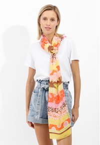 Écharpe en soie colorée présentant des motifs orange, rose et marron. Légère avec une texture lisse, elle rehausse les tenues décontractées.