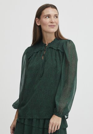Green, sheer blouse with a textured pattern, elasticized neckline, and long sleeves. Notable ruffled detailing at the shoulders.
