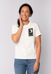 Witte katoenen T-shirt met een zwarte grafische print van een maan en sterren. Korte mouwen, ronde hals en een comfortabele pasvorm. Gekocht met blauwe jeans.