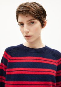 Marinblauer Pullover mit roten Streifen, aus weichem Strickmaterial; mit rundem Halsausschnitt und gerippten Akzenten an den Schultern.
