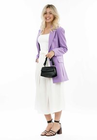Blazer lila, blusa blanca y pantalones anchos blancos; bolso negro con un asa texturizada; tacones negros con tiras y tacón amplio.