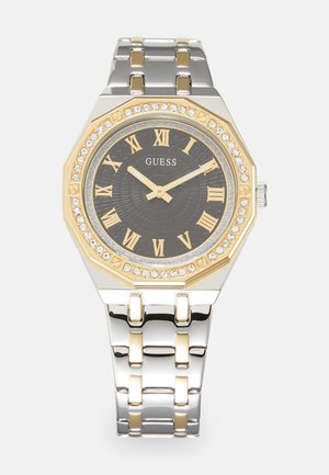 Osmerokutni ručni sat od nehrđajućeg čelika s dvobojnom srebrnom i zlatnom narukvicom. Crni brojčanik ima zlatne rimske brojeve i kristalne detalje.