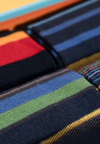 Calze colorate a strisce con strisce di diverse larghezze in blu navy, rosso, verde, blu e giallo, realizzate in un morbido tessuto a maglia testurizzato.