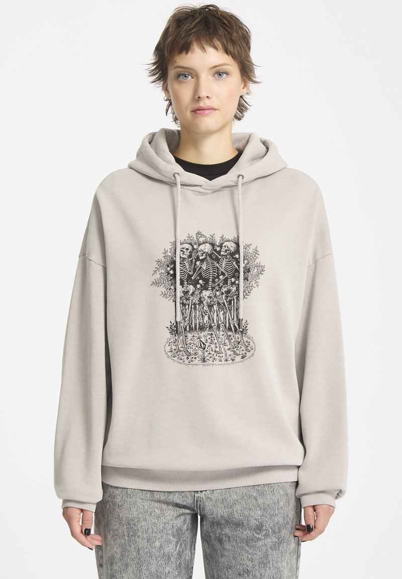 Lys beige hoodie med et stort sort skeletgrafik. Har en kængurulomme og hætte med snoretræk, lavet af blødt stof.