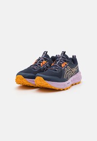 Marineblå sportsko med en teksturert overdel, oransje detaljer, reflekterende elementer, lilla såle og en robust, oransje yttersåle for godt grep.