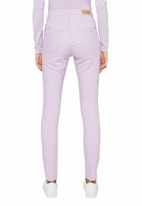 Fialové skinny džíny s hladkou strukturou, mají dvě zadní kapsy a hnědou koženou značku na opasku. Nosí se s bílými teniskami.