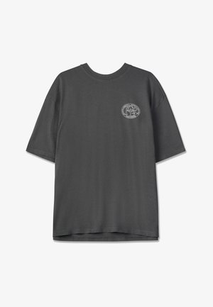 Tmavě šedé tričko s krátkým rukávem vyrobené z bavlny, s kulatým výstřihem a malým logem umístěným v levém horním rohu přední části. Hladká textura.