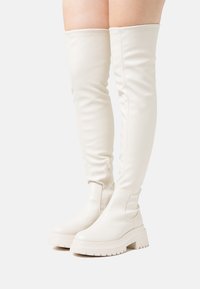 White, knee-high, fitted boots in smooth synthetic material. Chunky sole with a tread pattern, featuring a side zipper for easy wearing.