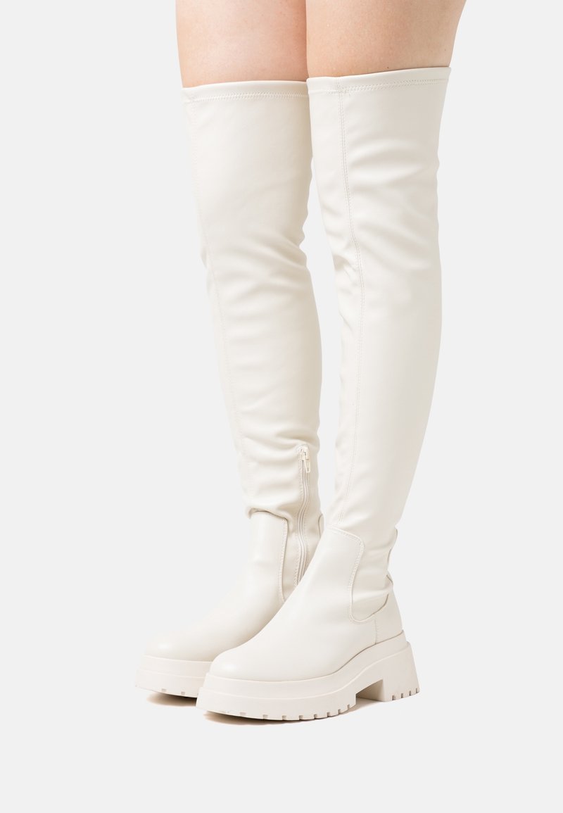 White, knee-high, fitted boots in smooth synthetic material. Chunky sole with a tread pattern, featuring a side zipper for easy wearing.
