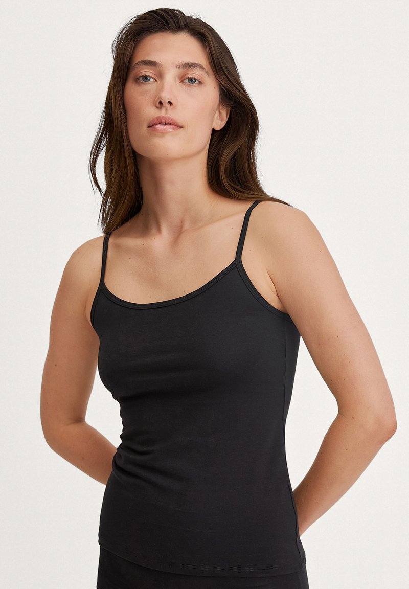 Débardeur noir à fines bretelles, fabriqué à partir d'un tissu doux et extensible. Présente un design ajusté et une texture lisse, idéal pour le superposition.
