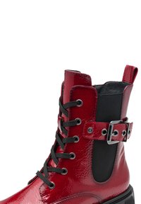Rote Lackleder-Ankle Boots mit schwarzen Schnürsenkeln, einem Schnallenriemen und elastischen Seitenpaneelen. Glänzende Oberfläche mit einer stabilen Sohle.