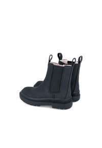 Botines negros con paneles elásticos, textura suave, punta redondeada y acentos en rosa contrastante en el borde superior y en las lengüetas.