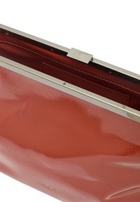 Borsa a mano in pelle verniciata rossa con finitura lucida, dotata di una chiusura in metallo argentato, tasca interna e texture liscia.