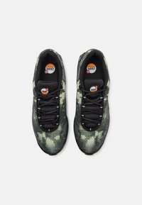 Schwarze Sportschuhe mit einem grün-schwarzen gepunkteten Muster, ausgestattet mit einem runden Logo, sechs Schnürsenkeln und einem gepolsterten Schaftrand für zusätzlichen Komfort.