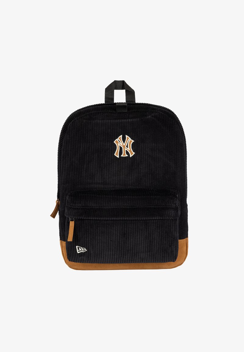 Sac à dos en velours côtelé noir avec base en daim marron, poche avant, et logo des New York Yankees brodé en beige et blanc sur le devant.