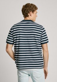 Striped polo shirt in navy and white, featuring short sleeves and a classic collar. Made of soft fabric with a relaxed fit.