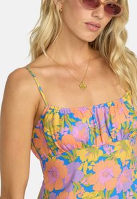 Bloemprint jurk met levendige kleuren zoals oranje, roze en blauw, met dunne schouderbandjes en een geplooid halsdetail.